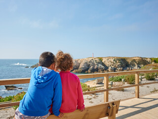 a couple of brother seated next to each other looking to the sea