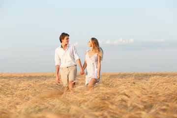 A couple in love in the summer walks in a cereal field