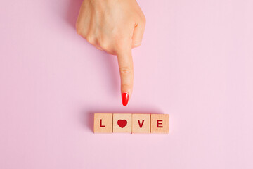 Relationship concept on pink background flat lay. finger showing wooden letter cubes.