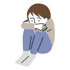 沈んだ表情で、うずくまって座る少年