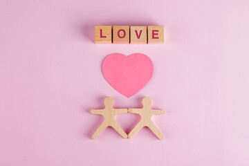 Relationship concept with paper cut heart, wooden cubes, human models on pink background flat lay.