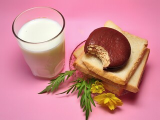 Dry rusk bread, choco pie chocolate and a glass of milk isolated on pink background. Healhty breakfast menu