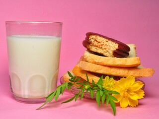 Dry rusk bread, choco pie chocolate and a glass of milk isolated on pink background. Healhty breakfast menu
