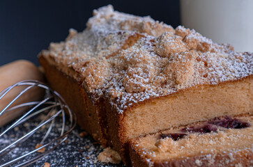 Exquisite red fruit bread, cream cheese, orange and almonds dusted with sugar on a black table with a black background.