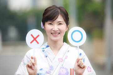〇×札を持つ浴衣女性
