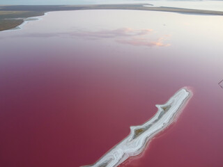 Reflection of clouds in the sky in the pink water of a lake that has pink water color and high salt content.