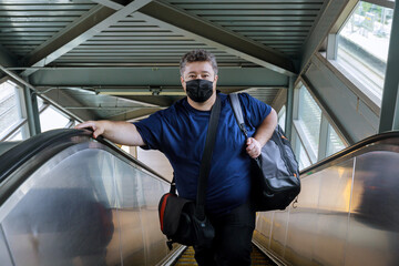 Man wear surgical face mask for protecting coronavirus, stand on the escalator, travel to the train, COVID-19