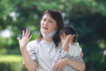 子供を抱っこし暑そうな母親