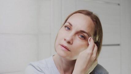 Adult woman applying lotion and looking at the camera