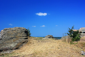 Stone granite rocks in the steppe under the blue sky