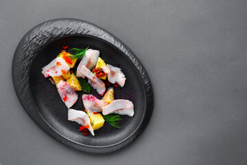 Cold appetizer salted herring with boiled potatoes on black plate