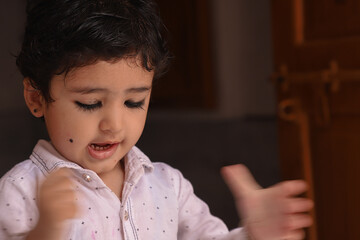 Very Cute Indian Kid Giving Pose To Camera With A Lovely Smile.