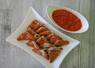 Breaded mozzarella cheese triangles with marinara sauce for dipping.