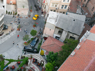 Top down view of tiled roofs, streets with people and parked cars