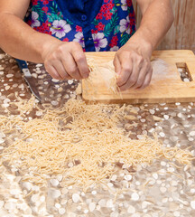 A woman sprinkles noodles cut from dough
