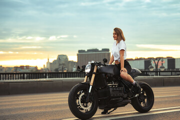 Fototapeta na wymiar Biker sexy woman sitting on vintage custom motorcycle. Outdoor lifestyle portrait