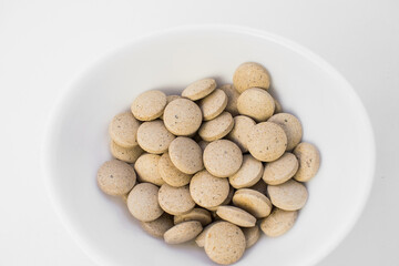 Top view of round yellow tablets in a white Cup