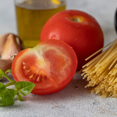 Italian food concept. Dry spaghetti, fresh tomatoes, basil, olive oil and garlic principal ingredients  in  Italian cuisine.