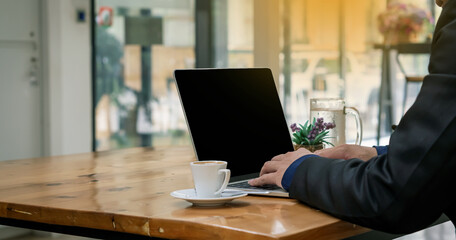 A businessman working on a laptop and with a coffee mug next to it and orange light