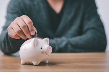 Obraz na płótnie Canvas business finance saving and investment concept. hand put money coin into piggy bank for saving money wealth.