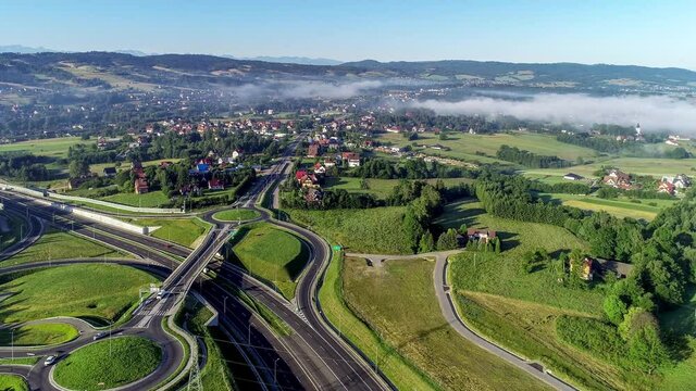 New motorway junction in Poland on national road no 7, E77, called Zakopianka.  Overpass crossroad with traffic circles, viaducts  and slip roads near Rabka. Aerial video. Far view of Tatra Mountains