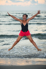 Woman jumping with arms open at sea