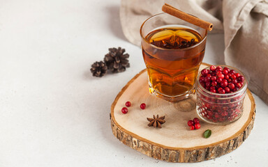 Hot tea with spices, Apple and berries in a transparent glass mug on a wooden stand. concept home comfort. Copy space