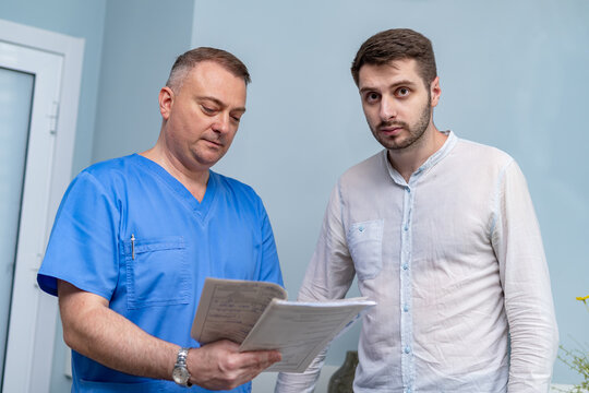 Doctor pointing on results of a patient`s health diagnosis. Discussing health care issues. Medic and patient in office.