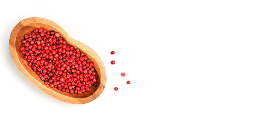 Red or Pink peppercorn in small wooden bowl, some scattered on board near, closeup photo from above isolated with white background