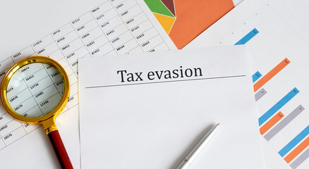Tax evasion written on a paper whith charts