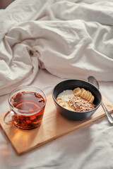Good morning. Breakfast in bed. Bowl of granola and cup of hot tea.