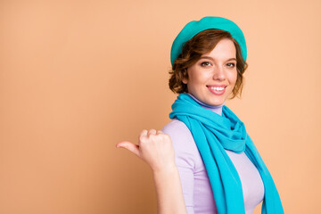 Close-up portrait of her she nice attractive lovely pretty confident cheerful cheery girl pointing thumb aside choose choice ad advert decision copy space isolated over beige pastel color background