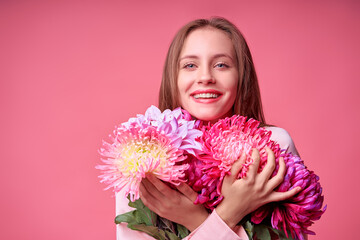 Fototapeta premium Young woman with bouquet on pink background. Happy laughing girl holding bunch of flowers. Vivid bright colors concept.