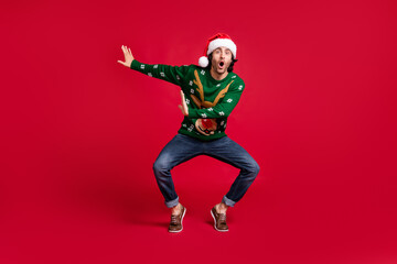 Fototapeta na wymiar Full length body size view of attractive comic childish glad cheerful cheery funny youth guy wearing Santa hat dancing having fun rest chill isolated bright vivid shine vibrant red color background