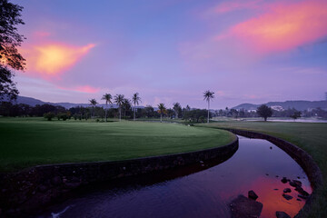 Beautiful sunset on curvy pond in a huge park full of plantlife.