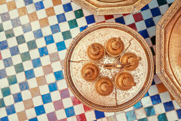 Top view on moroccan brazen tablewear with tiled background.