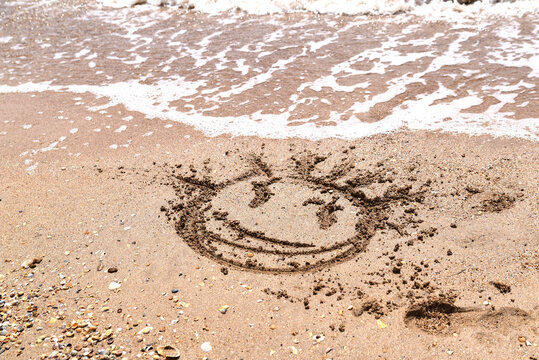 image of a face on the sea sand