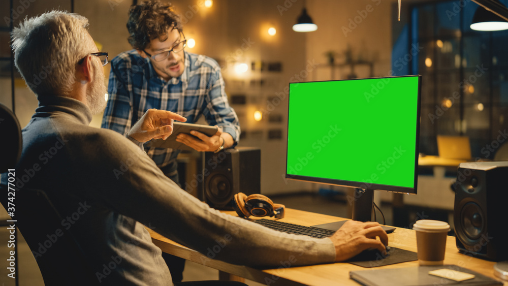 Poster in the evening creative middle aged man works on a desktop computer green mock-up screen, has conver