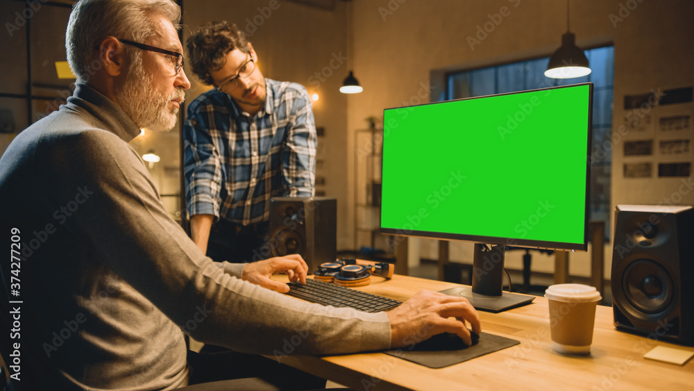 Poster in the evening creative middle aged man works on a desktop computer green mock-up screen, has conver