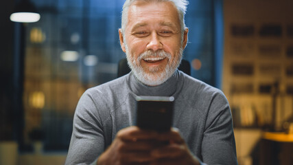 Portrait of Handsome and Successful Middle Aged Bearded Businessman Uses Smartphone Laughs and...