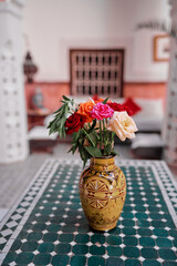 Roses in vase on tiled table.