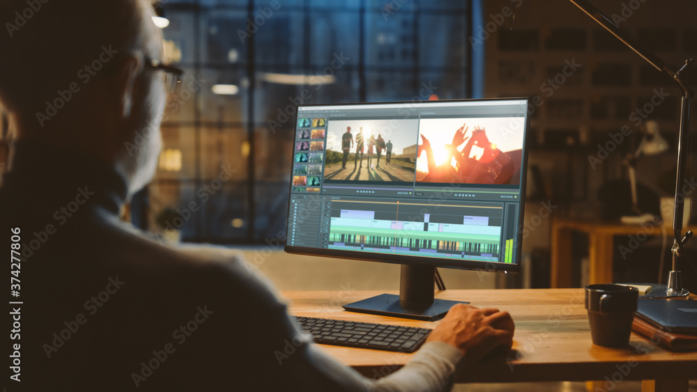 Poster over th shoulder shot: professional middle aged videographer works on desktop computer, doing footag