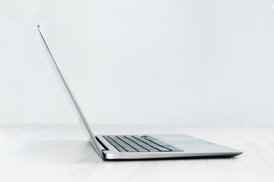 Side view of slim silver laptop on a grey desk. Copy space. Minimal. Mockup