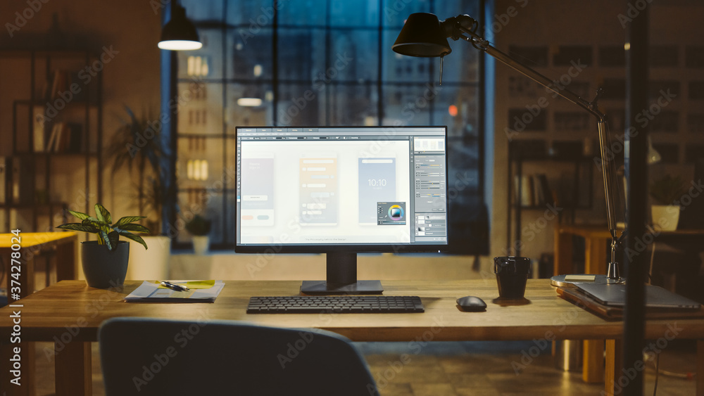 Poster Shot of a Desktop Computer in the Office Shows Screen with Mobile Phone Application Design, Software UI Development. In the Background Warm Evening Lighting and Open Space Studio with City Window View