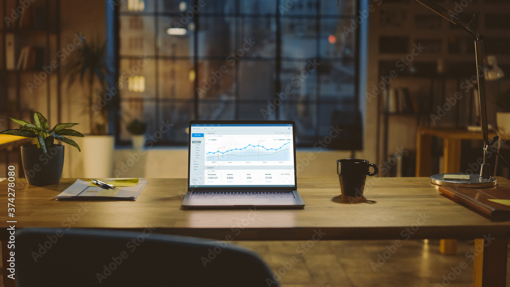 Poster Shot of a Laptop on a Desk with Statistics Graph, Chart and Various Data, Showing Company Growth and Success. In the Background Businessman Drinks from a Cup Looks at the Night City out of the Window
