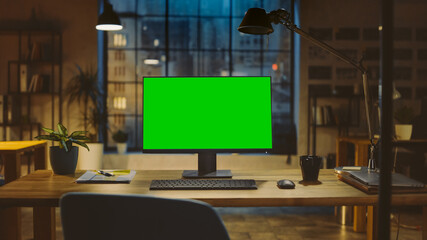 Desktop Computer with Mock-up Green Screen Standing on the Wooden Desk in the Modern Creative...