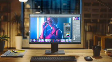 Shot of a Desktop Computer in the Modern Office with Monitor Showing Photo Editing Software. In the Background Warm Evening Lighting and Open Space Studio with City Window View - obrazy, fototapety, plakaty