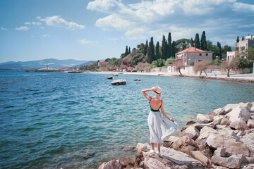 Tourism concept. Young traveling woman enjoying the view of Kastel Castle walking near the sea on...