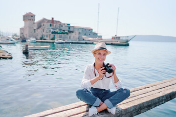 Tourism concept. Young traveling woman enjoying the view of Kastel Gomilica Castle sitting near the sea on Croatian coast.