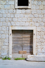 Ancient stone wall of old building with wooden vintage door.